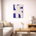 北欧ミニマルなリビング空間に飾られた、ブルーシェイプの抽象アート（A3サイズ相当）。