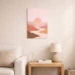 北欧ミニマルなリビング空間に飾られた、ピンクサンセットと川の流れを描いた抽象風景アート（A3サイズ相当）。
