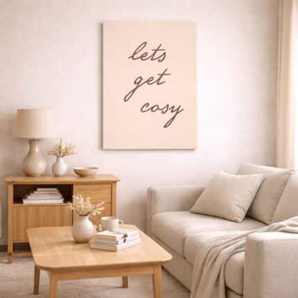 北欧ミニマルなリビング空間に飾られた「Let’s Get Cozy」のタイポグラフィアート（A3サイズ相当）