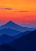 夕焼け空と青い山並みを描いた夕映えの峰の風景アートパネル